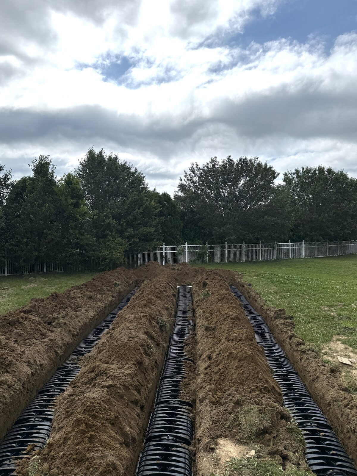 Long septic drain field trenches along a fence line